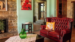 A cozy room with a fireplace, a red leather sofa, a green vase, and a painting of red flowers on the wall. - Beautiful private villa with WIFI, private pool, TV, terrace, pets allowed and panoramic view (Trivigno)