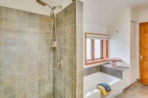 Et badeværelse med bruser, badekar og et vindue med skodder.