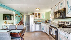 Una cocina equipada con refrigerador, lavavajillas, estufa y microondas. Cuenta con un comedor con mesa y sillas.