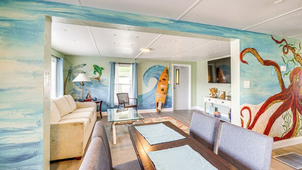 Una sala de estar con un mural de una tabla de surf, un sofá, una mesa de centro y un televisor.