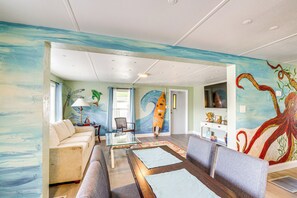 Una sala de estar con un mural de una tabla de surf, un sofá, una mesa de centro y un televisor.