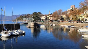 A marina with boats docked, a stone pier, and buildings with a church steeple in the background.
