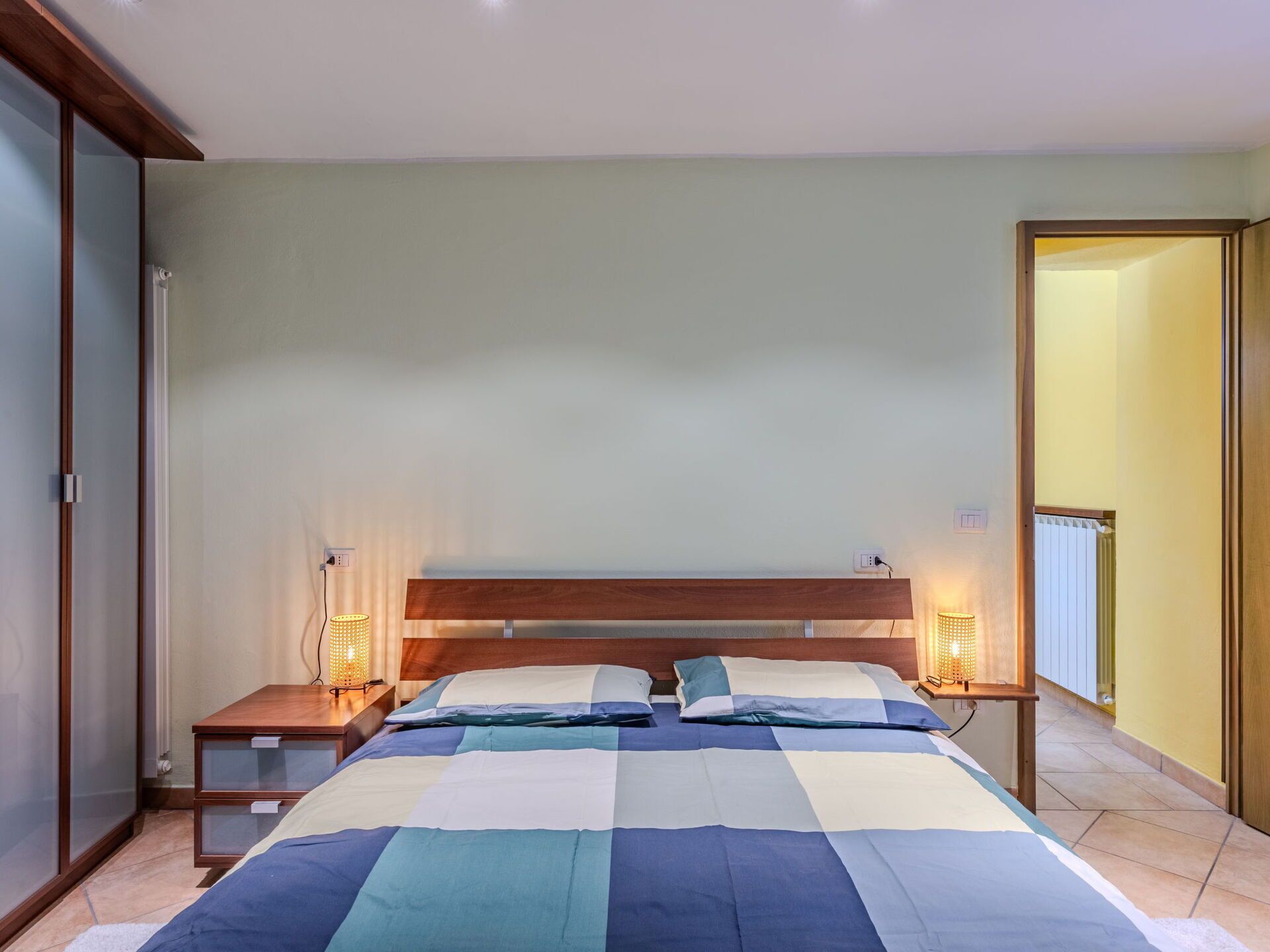 Um quarto com uma cama, duas mesas de cabeceira e um criado-mudo.