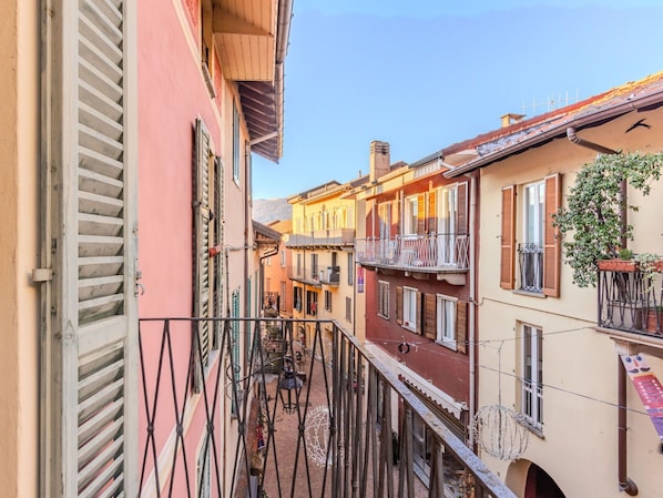 A narrow alleyway between buildings with balconies, a small courtyard, and a clear sky.