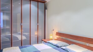 Ein Schlafzimmer mit Bett, Nachttisch und Kleiderschrank mit Milchglasschranktüren.
