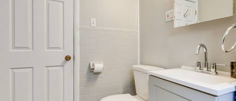 A bathroom with a white toilet, a sink with a chrome faucet, and a mirror above the sink.