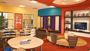 A children's play area with tables, chairs, and a television. - Orlando | Easy Disney Retreat | Pool + Parks (Orlando)