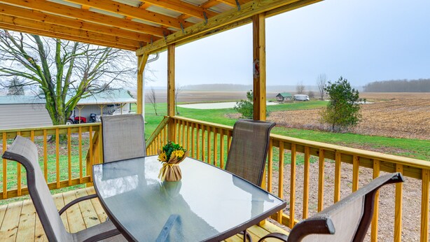 Een overdekt terras met een glazen tafel en stoelen, met uitzicht op het buitengebied.