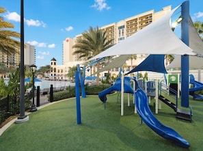 A playground with slides and a pool in the background. - Orlando | Family Park Retreat | Pool + Parks | 2BR (Orlando)