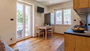 A compact kitchen with a dining area, a built-in TV, and a large window. - Lovely apartment for 3 guests with A/C, WIFI and balcony (Novate Mezzola)