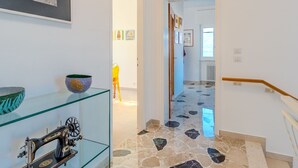 A hallway with a sewing machine on a glass shelf, a framed picture on the wall, and a tiled floor. - Lovely apartment for 6 guests with WIFI, TV and patio (Germignaga)