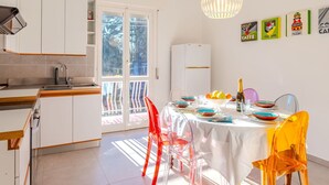 A modern kitchen with white cabinets, a built-in oven, and a dining area with a white table and clear chairs. - Lovely apartment for 6 guests with WIFI, TV and patio (Germignaga)