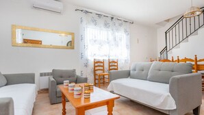 A living room with two sofas, a wooden table with plates, a mirror, and a staircase. - Wonderful private villa for 8 people with private pool, A/C, WIFI, TV and pets allowed (Vidreres)