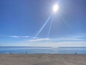 A beach with people sunbathing and a clear sky.