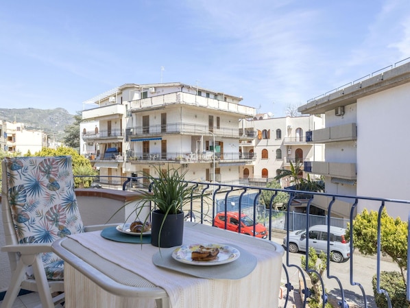 A balcony with a table set for two, a chair, and a potted plant.