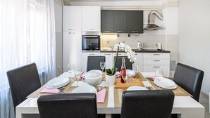 A modern kitchen with white cabinets, a built-in oven, and a large flat-screen TV.