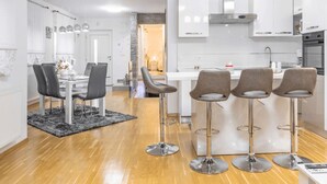Een moderne keuken met witte kastjes, roestvrijstalen apparatuur en een centraal eiland met barstoelen.