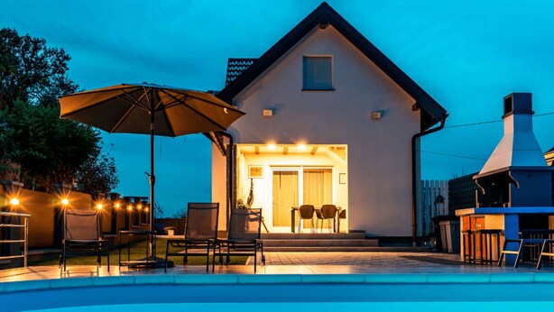 Een huis met een zwembad, een terras en een barbecueplek.