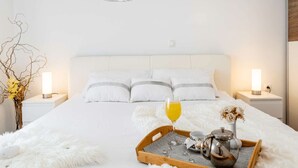 Een keurig opgemaakt slaapkamer met een groot bed, een nachtkastje met een lamp en een dienblad met ontbijtartikelen.