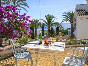 Enjoy a romantic dinner for two in this serene outdoor setting, complete with a bottle of wine, fresh fruit, and a beautiful ocean view.