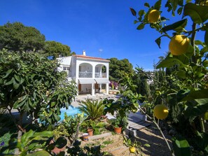 Stunning villa with a balcony overlooking a serene garden and pool area, surrounded by lush greenery and tropical plants.
