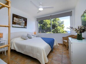 Relax in this serene bedroom with a large bed, ceiling fan, and stunning sea views.
