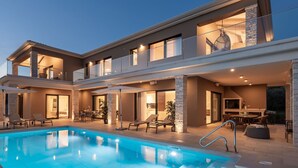 Ein modernes, zweistöckiges Haus mit Swimmingpool, Sitzgelegenheiten im Freien und einem großzügigen Essbereich.