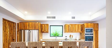 Une cuisine moderne avec des meubles en bois, un grand îlot central et un téléviseur à écran plat.