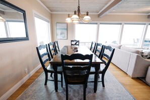 A dining area with a long table, chairs, and a chandelier.