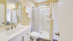 Een badkamer met een wit wastafel, toilet, douche met glazen deur en spiegel.