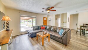 A living room with a sectional sofa, a wooden coffee table, a ceiling fan, and a dining area with a table and chairs. - Pet-Friendly San Antonio Vacation Rental w/ Pool! (San Antonio)