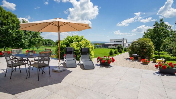 Une terrasse extérieure avec une table et des chaises, un grand parasol et des plantes en pot.