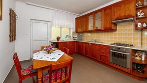 Une cuisine de taille réduite, dotée de meubles de rangement en bois, d’une cuisinière à gaz et d’une table à manger avec des chaises.