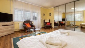 Une chambre d’hôtel avec un grand lit, une télévision, une chaise et une table basse en verre.