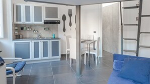 Um espaço compacto com cozinha americana, área de jantar e um sofá azul.