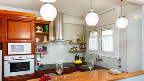 Eine Küche mit Holzausstattung, einer Mikrowelle, einem Backofen, einer Spüle und Pendelleuchten.