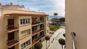 Ein mehrstöckiges Gebäude mit Balkonen, einem Ziegeldach und Blick auf das Meer.
