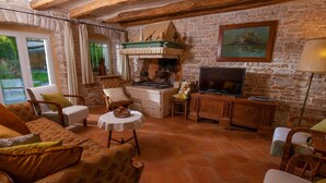 A cozy living room with a stone fireplace, comfortable seating, and a television. - Wonderful private villa for 12 guests with WIFI, A/C, private pool, TV, terrace and pets allowed (Pazin)
