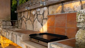 An outdoor kitchen with a stone wall, built-in grill, and overhead lighting. - Wonderful private villa for 12 guests with WIFI, A/C, private pool, TV, terrace and pets allowed (Pazin)