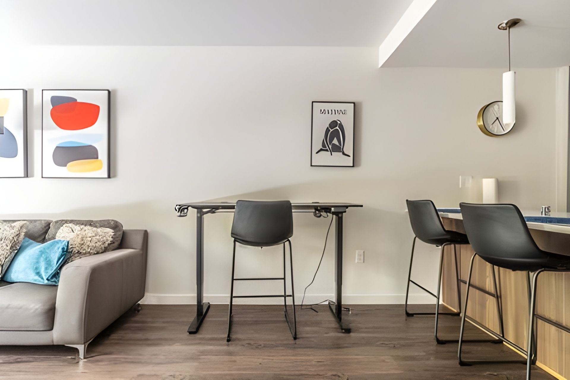 A modern living room with a sofa, a dining table with chairs, and artwork on the walls.