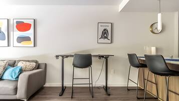 A modern living room with a sofa, a dining table with chairs, and artwork on the walls.