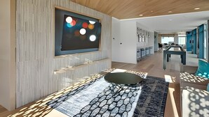 A modern interior with a wooden ceiling, a large abstract painting, and a patterned rug. - 1BR+Den | Gym | Bellevue | Sophari Downtown D (Bellevue)