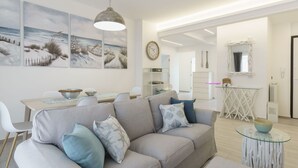 Ein modernes Wohnzimmer mit grauem Sofa, einem Esstisch und Bildern an der Wand.