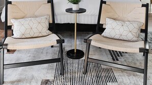 A bedroom with a bed, two chairs, a small table, and a ceiling fan. - | Downtown Nash | Outlaw Theme | Large Groups | (Nashville)