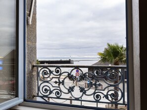 Enjoy the serene coastal view from this balcony with a decorative railing and scenic views of the water, pier, and palm tree.