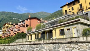 A row of colorful buildings with stone walls, balconies, and a mountainous backdrop. - Wonderful private villa for 5 guests with pool, WIFI, TV and patio (Bellano)