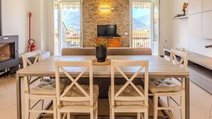 Un comedor con una mesa larga, sillas, un televisor y una pared de piedra.
