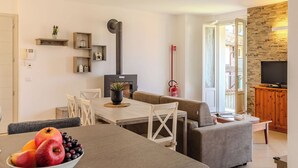 Una sala de estar moderna con comedor, chimenea y pared de piedra.