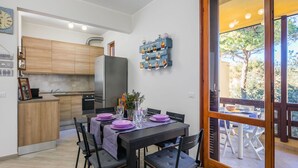 Una cucina moderna con mobili in legno, un frigorifero in acciaio inossidabile e un'area pranzo con tavolo imbandito per quattro persone.
