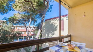 Un balcone con un tavolo apparecchiato per due, con vista su una zona residenziale alberata e con edifici.